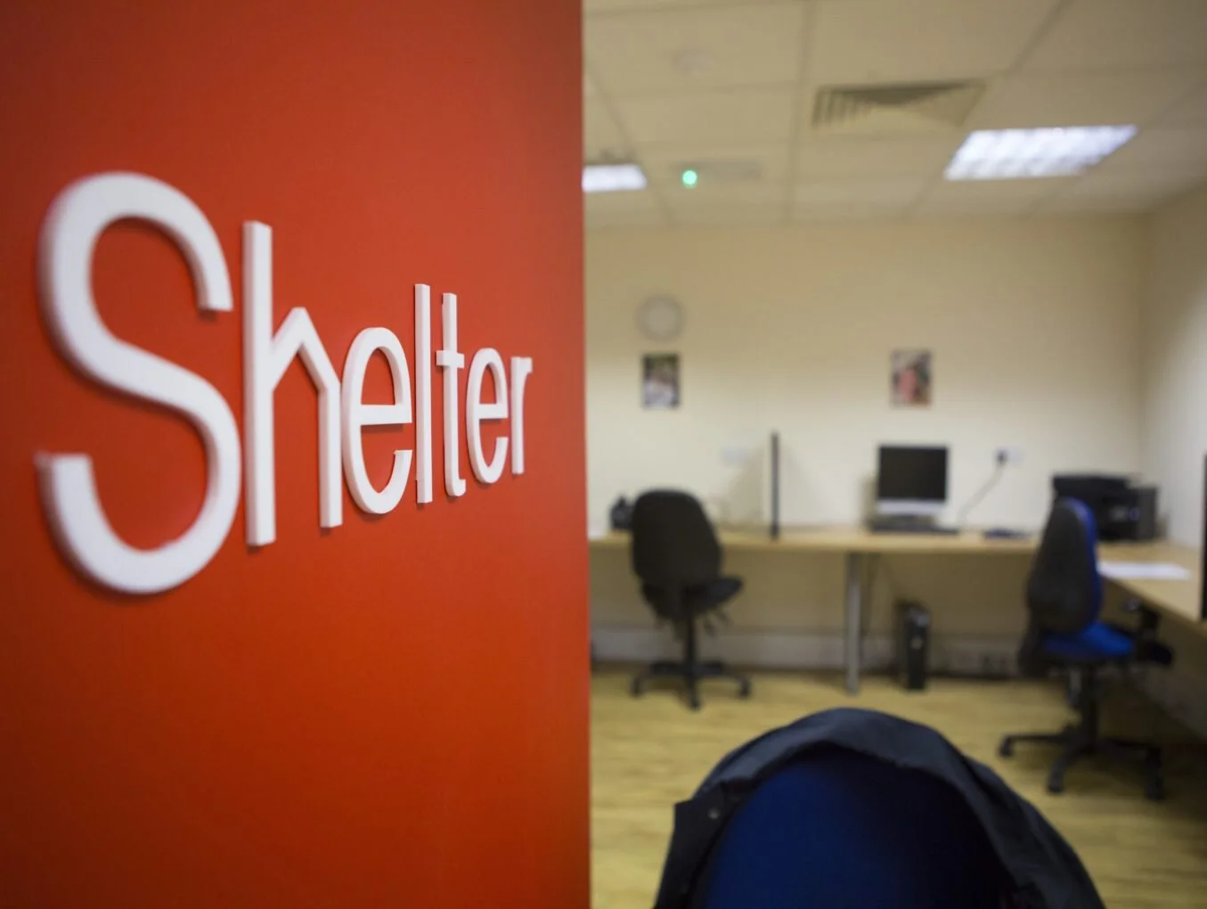An empty Shelter office with the red Shelter sign on the wall.